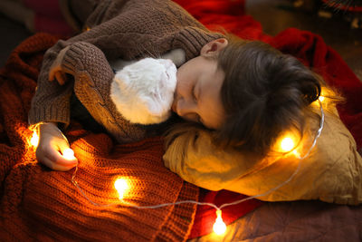 Girl child sleeps in an embrace with a cat blanket and a garland,