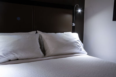 Close-up of illuminated electric lamp on bed at home