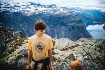 High angle view of young man smiling while standing at trolltunga during winter