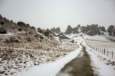 Road amidst landscape against clear sky during winter