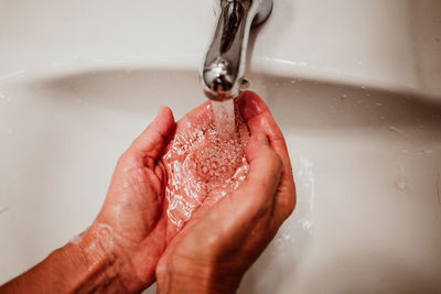 Cropped image of man washing hands in sink