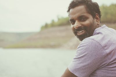 Portrait of smiling young man against sky