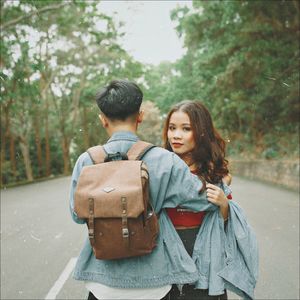 Rear view of couple and woman against trees