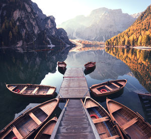 Boats moored around jetty in lake against mountains