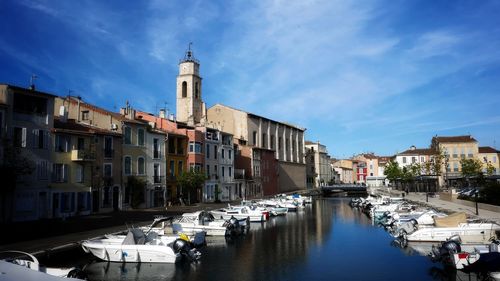 Boats moored in canal amidst buildings in city