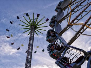 Low angle view of ferris wheel against cloudy sky