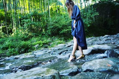 Full length of man standing on rock in forest