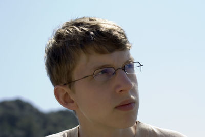 Close-up of thoughtful teenage boy looking away against clear sky