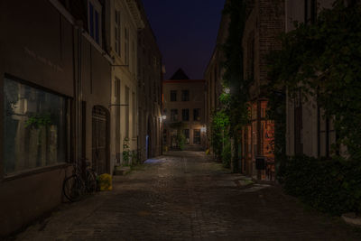 Illuminated cobbled street amidst buildings at night