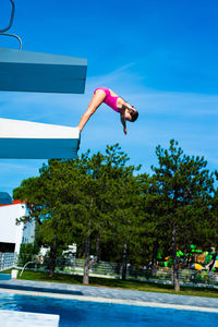 Man jumping in swimming pool against blue sky