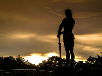 Silhouette statue against cloudy sky