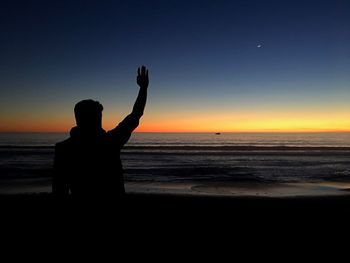 Silhouette man on beach against sky during sunset