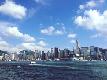 Sea by modern buildings in city against sky