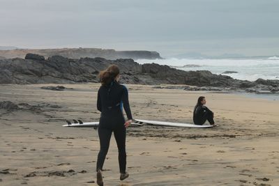 Rear view of surfer running on shore at beach