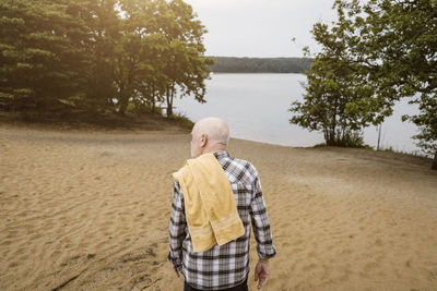 Rear view of senior man with towel on shoulder walking towards river