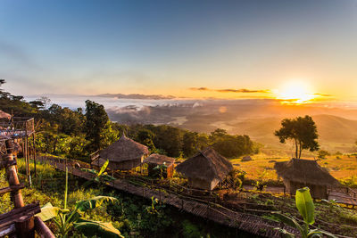 Scenic view of trees and houses against sky during sunset