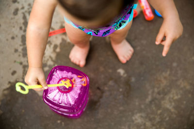 High angle view of girl plying with bubble wand while standing outdoors