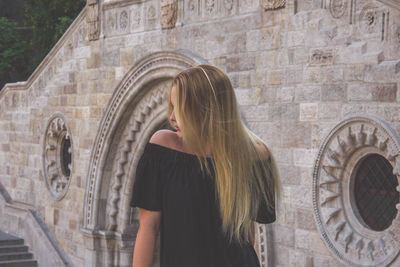 Young woman standing against historical building