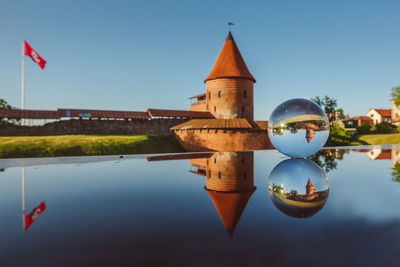 Reflection of built structures on crystal ball against clear blue sky