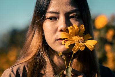 Close-up portrait of woman with red flower