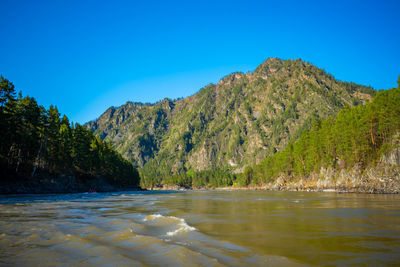 Scenic view of lake and mountains against clear blue sky