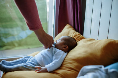 Cropped woman holding pacifier in boy mouth