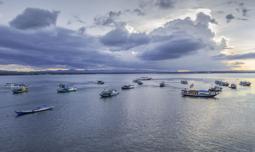 Sailboats moored on sea against sky during sunset