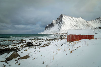 Snow covered land and sea against sky