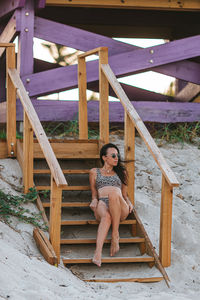 Young woman sitting on railing