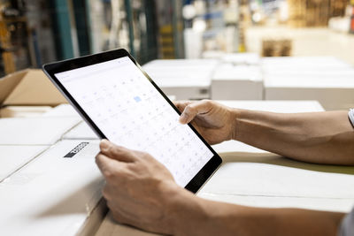 Hands of worker checking inventory on tablet pc in warehouse