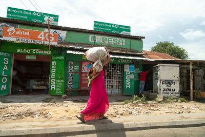Woman standing by text on wall against sky