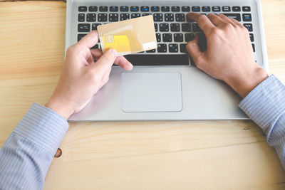 Midsection of man using mobile phone on table