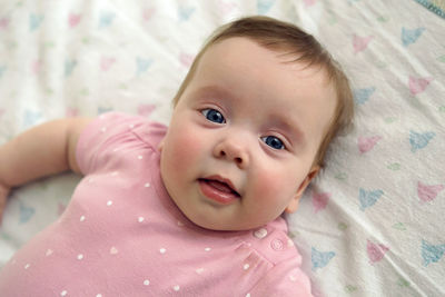 Portrait of cute baby boy lying on bed at home