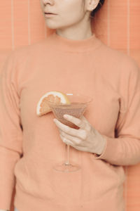 Crop unrecognizable female with glass of refreshing pink martini cocktail with chia seeds and grapefruit slice