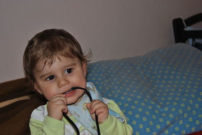 Cute baby boy biting cable at home