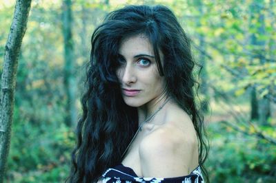 Portrait of young woman against tree trunk