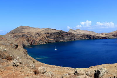 Scenic view of sea and mountains against blue sky