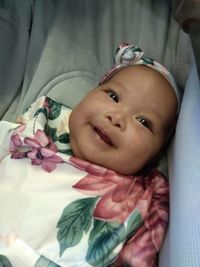 Portrait of cute baby girl lying on bed