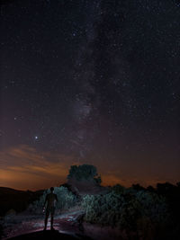 Rear view of man standing against sky at night