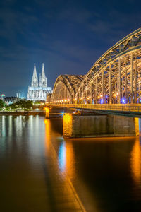 Illuminated bridge over river at night