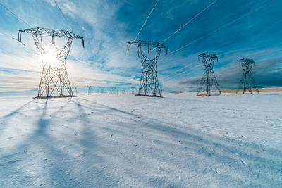 Electricity pylon on field against sky