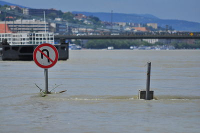 Road sign amidst water during flood in city