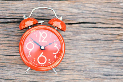 Close-up of red alarm clock on wooden table