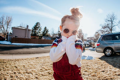 Young girl in front yard with sunglasses on