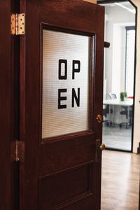 Close-up of text on wooden door of open business