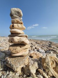 Stack of stones on beach against sky