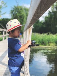 Side view of boy holding umbrella against lake