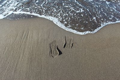 High angle view of footprints on wet sand