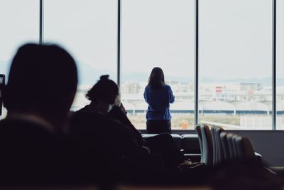 Rear view of woman standing by window at airport