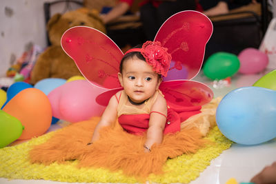 Cute baby girl by colorful balloons during celebration at home